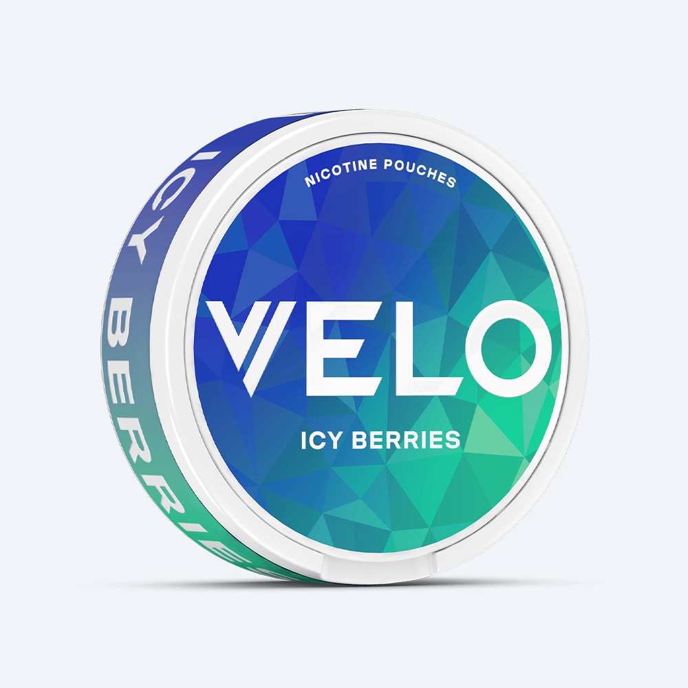 Round container of VELO Icy Berries nicotine pouches with a blue and green geometric background, featuring the brand name and flavor text.