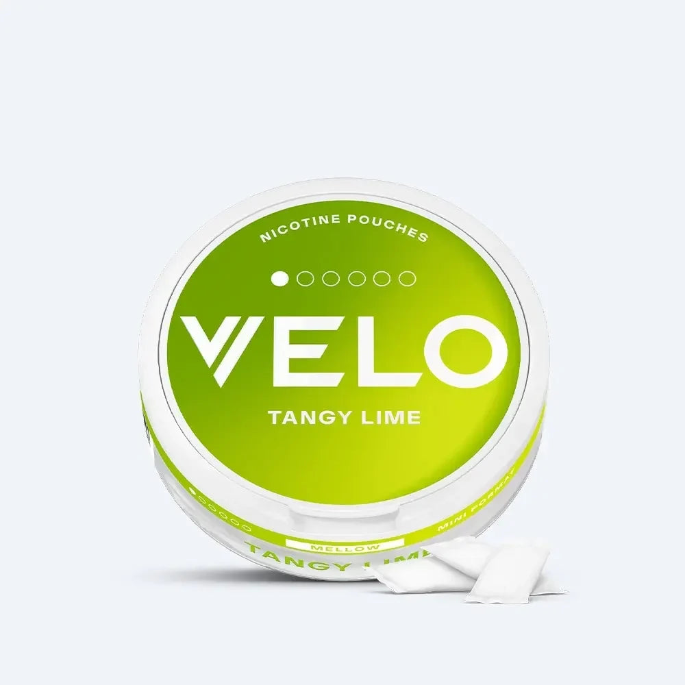 Velo Nicotine Pouches |  A round container labeled VELO Tangy Lime Nicotine Pouches with a green and white design sits on a plain light background. Two white Velo nicotine pouches are displayed in front of the container, highlighting their clean and convenient form.